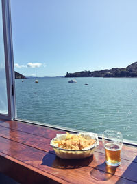 Close-up of drink on table by sea against sky