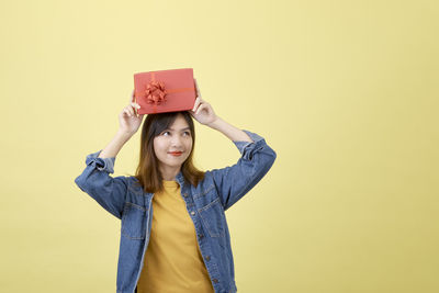 Portrait of woman standing against yellow background