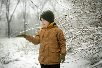 Rear view of boy standing in snow. catch snowflakes. children winter fun
