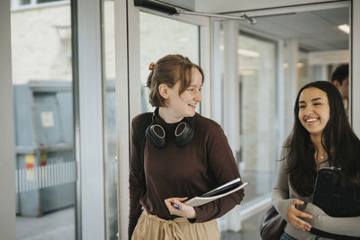 Smiling female friends entering classroom in university