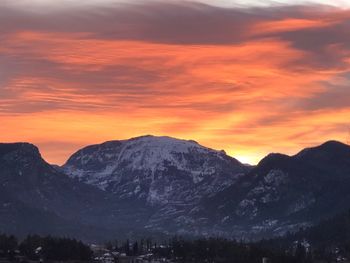 Scenic view of snowcapped mountains against orange sky