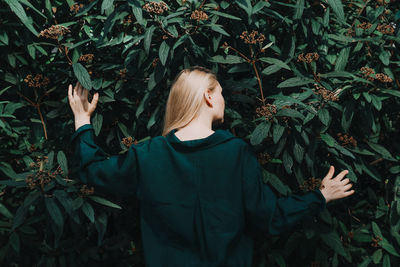 Rear view of woman standing amidst plants