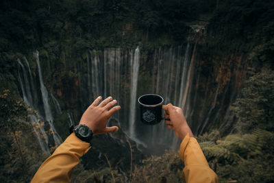 Midsection of man holding rock in forest
