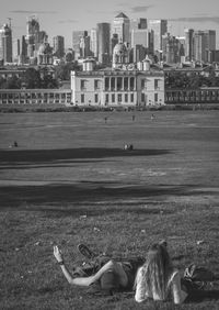 Sea and woman lying on shore against buildings in city