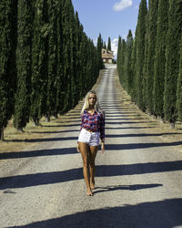 Full length portrait of woman walking on road amidst trees