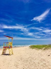 Lifeguard hut on beach against blue sky