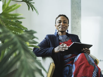 Stylish businesswoman with tablet pc sitting on chair at office