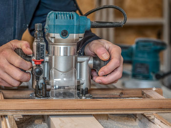 Carpenter planing a plank with a router using a jig