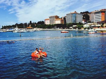 People in boat on sea against sky in city