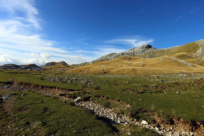 Scenic view of land and mountains against blue sky