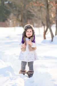 Portrait of happy girl standing on snow