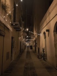 Empty alley amidst buildings in city at night