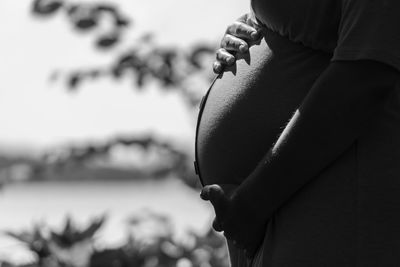 Midsection of pregnant woman against tree