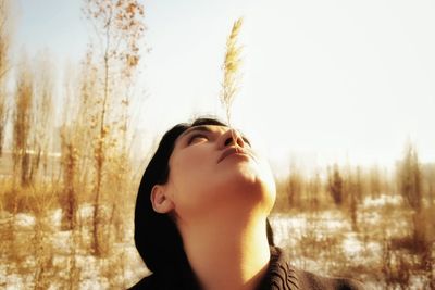 Portrait of young woman looking away against sky