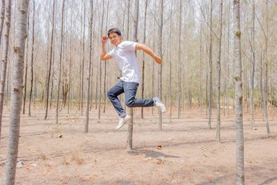 Full length portrait of young man jumping at forest