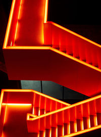 Red illuminated metal staircase at night on the industrial site