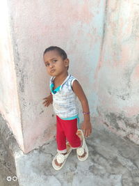 Full length of cute girl standing against wall