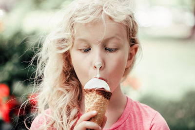 Cute funny girl with dirty nose eating licking ice cream. kid looking at food with crossed eyes