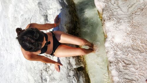 High angle view of woman sitting on rock in sea