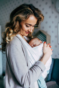 Mother carrying newborn son at home