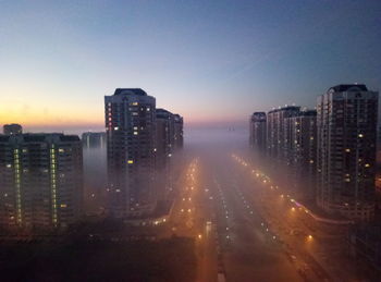 Illuminated cityscape against sky during sunset