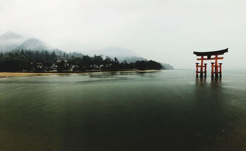 Tori gate in lake against sky