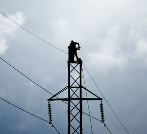 Silhouette man working on electricity pylon