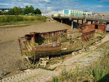 Abandoned boats on field against sky