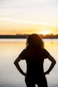 Rear view of man standing against sea during sunset