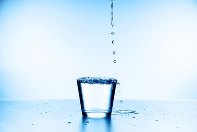 Close-up of water splashing on table against blue background