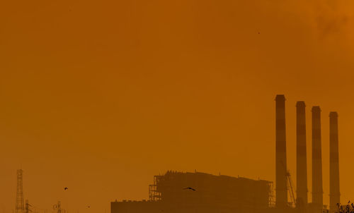 Power plant with orange sunset sky and birds flying on the sky. air pollution concept. 