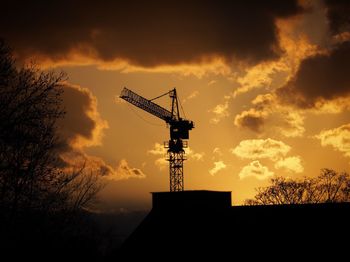 Low angle view of silhouette cranes against sky during sunset