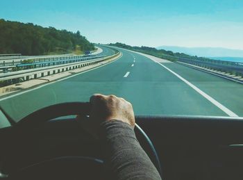 Man driving car on road against clear sky