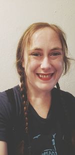 Portrait of smiling young woman against wall