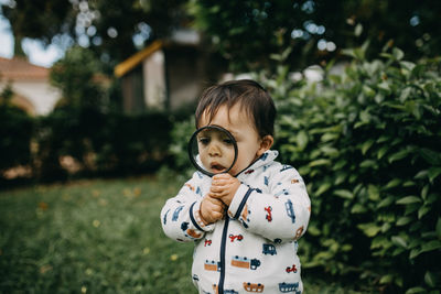 Cute boy standing playing with magnifying glass