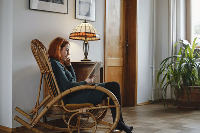 Woman on rocking chair reading book. relaxed home atmosphere. vintage house for slow living. female