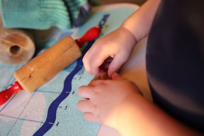 Cropped image of child preparing gingerbread cookie at table