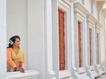 Side view of woman standing by window