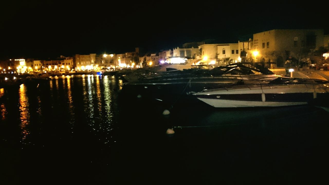 BOATS MOORED AT ILLUMINATED HARBOR IN CITY AT NIGHT