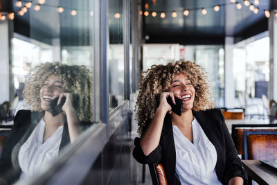 Smiling hispanic afro business woman in cafe working on laptop and mobile phone.business,lifestyle