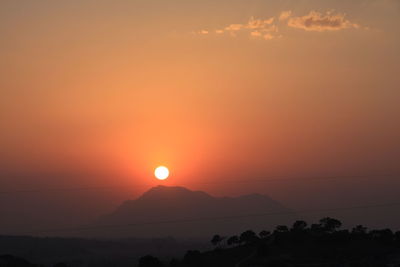 Scenic view of silhouette landscape against orange sky