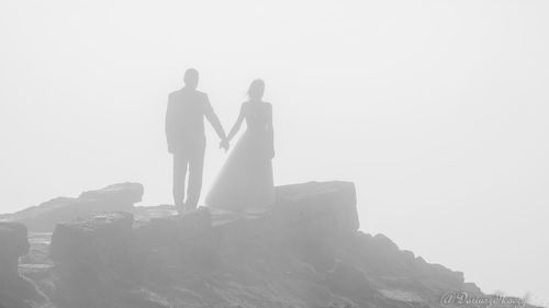 People standing on rock against sky