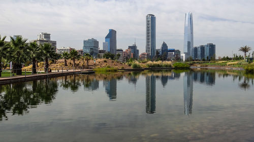 Reflection of buildings in lake against sky in city