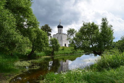 Reflection of trees and building in lake against sky