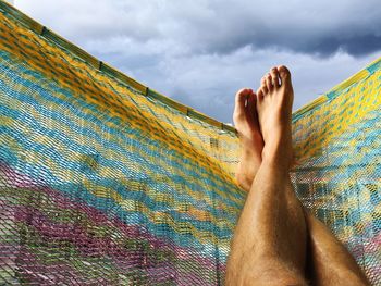 Low section of man relaxing against sky