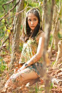Portrait of woman standing by tree in forest