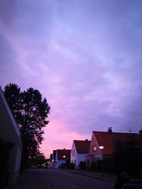 Street amidst buildings against sky at sunset