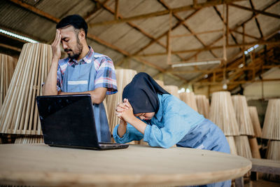 Young man using laptop while sitting on table