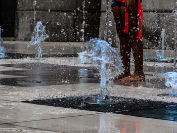 Low section of woman standing by fountain