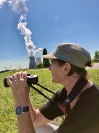 Man holding smart phone against sky